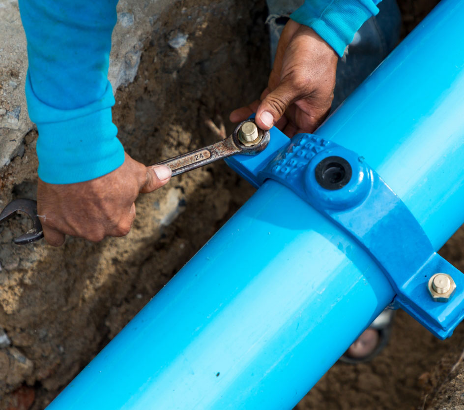 person tightening bolt on blue pipe